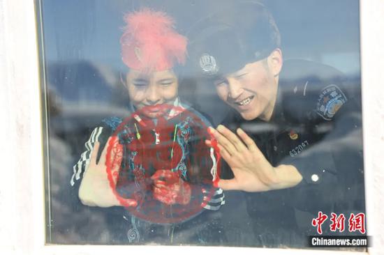 2023年大年初一，新疆维吾尔自治区阿勒泰地区富蕴县，民警与市民贴窗花。王友波 摄