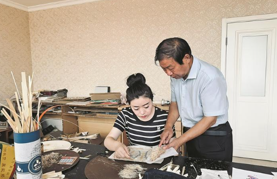 袁玉婷(左)正在向老师学习麦秸画制作工艺(资料图)。 袁玉婷 提供 袁玉婷(左)正在向老师学习麦秸画制作工艺(资料图)。 袁玉婷 提供